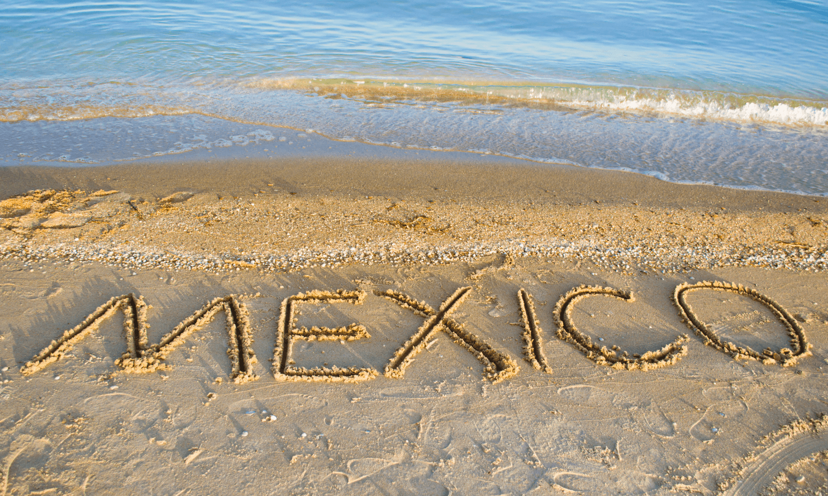 The word Mexico drawn in the sand on a beach on the Mexico Coast.