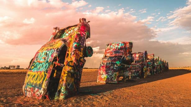 Row of half-buried, graffiti-covered Cadillacs in the desert at Cadillac Ranch art installation.