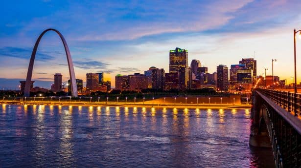St. Louis skyline at sunset with the Gateway Arch reflecting in the Mississippi River.