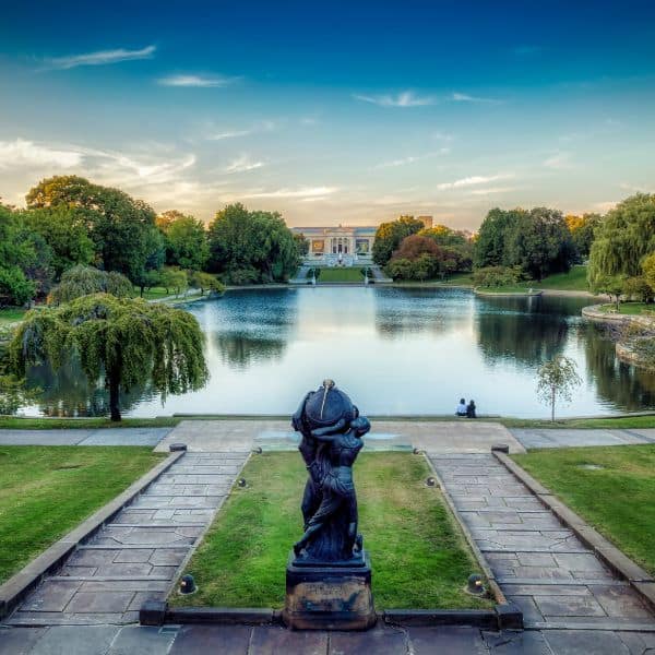 Scenic view of Cleveland with a reflecting pond, lush trees, and the Cleveland Museum of Art at sunset, highlighting the city’s cultural attractions.