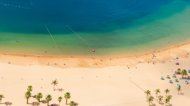 Sunny family-friendly beach in the Algarve with golden sand, clear turquoise water and people relaxing by the shore - one of Click&Go Holidays’ top destinations for families