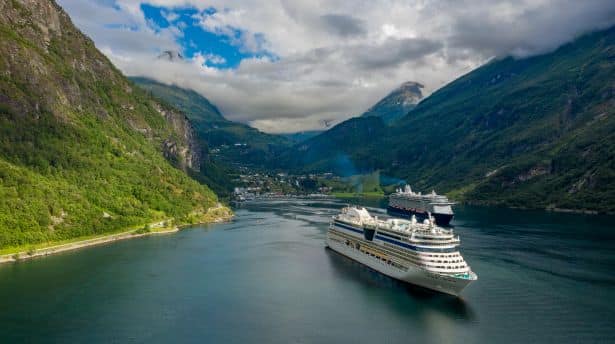 Cruise ship sailing through the Norwegian fjords surrounded by dramatic mountains and calm waters