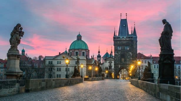 Charles Bridge in Prague at sunrise with historic towers and city skyline