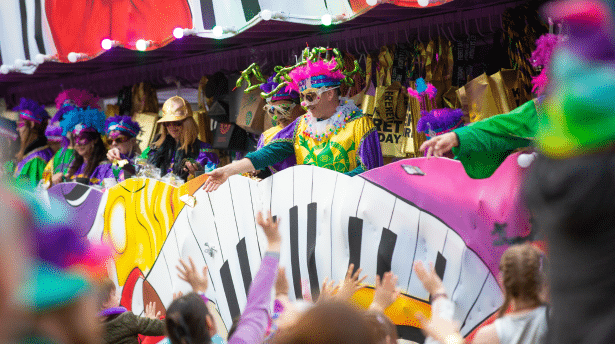 Colourful Mardi Gras parade in New Orleans with performers throwing beads from a vibrant float to cheering crowds