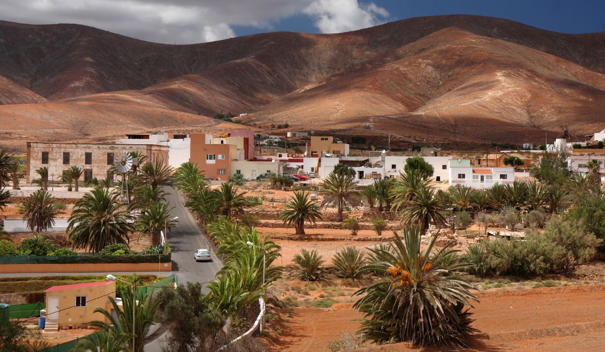 Picturesque view of a small village in Fuerteventura with colourful houses nestled between arid hills.  