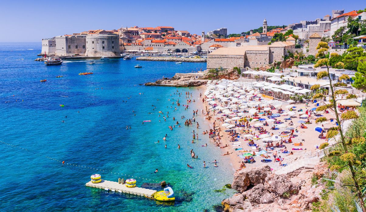 Busy summer day at the main beach in Dubrovnik with a view of the historic city walls.
