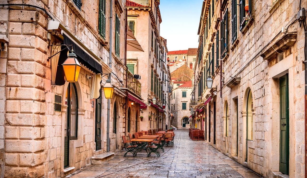 Empty morning streets in Dubrovnik Old Town with historic buildings and hanging lanterns.