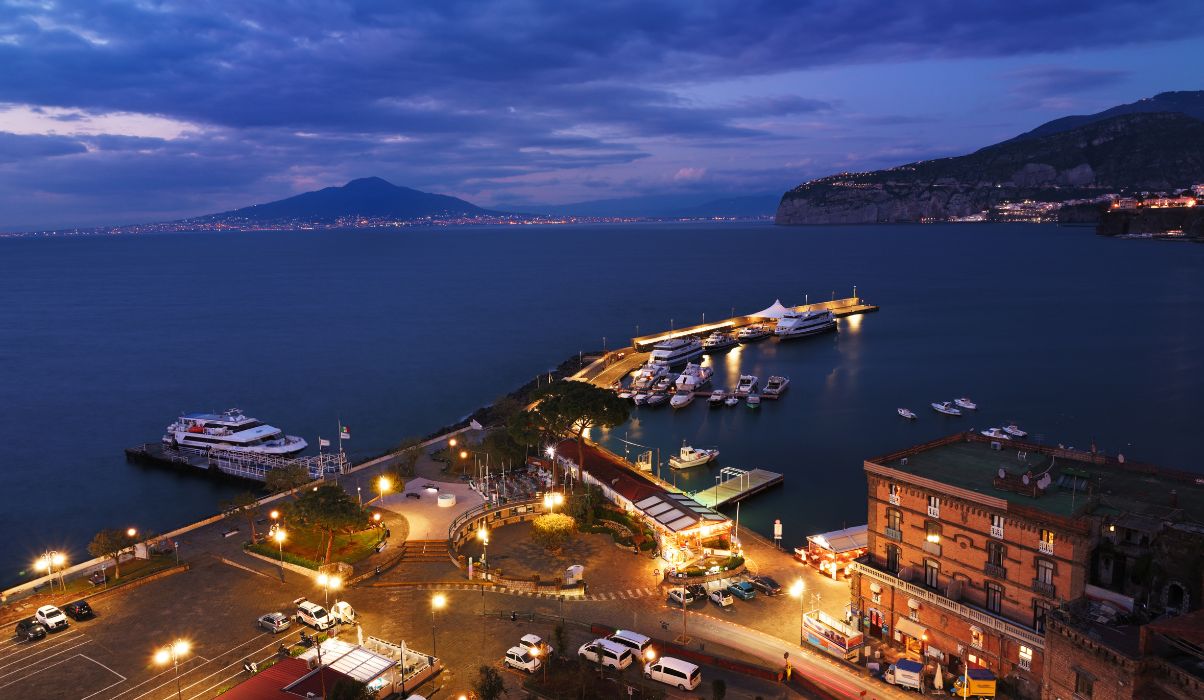 View of Sorrentos stunning marina with boats docked with a stunning backdrop at night.