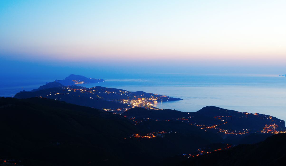 Image of Sorrento lighting up as the sunsets over the mountains featuring a bright orange sky.