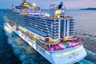 image from the back of the lit up MSC Seaview cruise ship as the sun sets there is a pink hue in the sky.